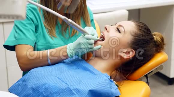 一位女牙医在一位年轻女子的牙齿上修修补补病人转过身来微笑成相机视频的预览图