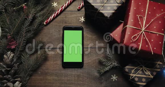上景黑色智能手机与绿色屏幕躺在桌子上与圣诞节假日装饰圣诞节假期视频的预览图