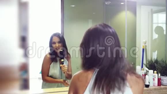 布鲁内特漂亮的女孩用镜子边的梳子嬉戏地唱歌慢动作3840x2160视频的预览图