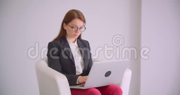 戴着眼镜的年轻白种人女商人的特写照片她用笔记本电脑看着镜头开心地坐着微笑视频的预览图