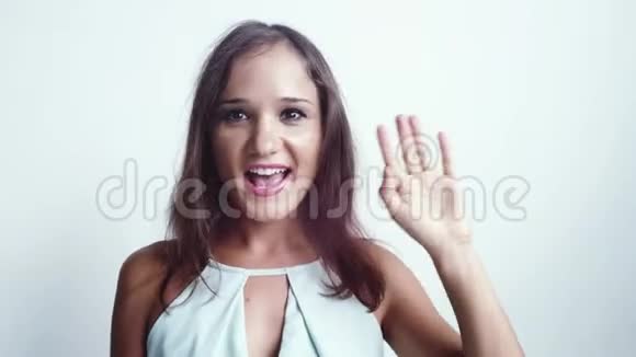 微笑的年轻女子追上她的社交媒体在白色的背景上挥舞着手3840x2160视频的预览图