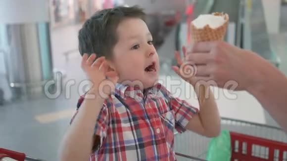 快乐的小男孩在购物车与美味的冰淇淋在家庭购物超市视频的预览图