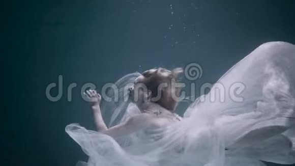 美丽的女人在水下游泳穿着白色优雅的衣服视频的预览图