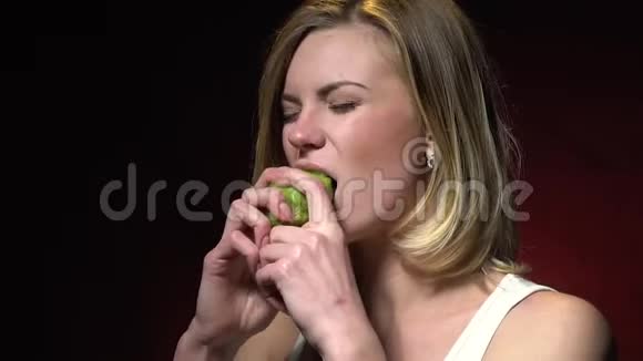 一个穿着白色T恤的快乐金发女郎正在吃奇异果视频的预览图
