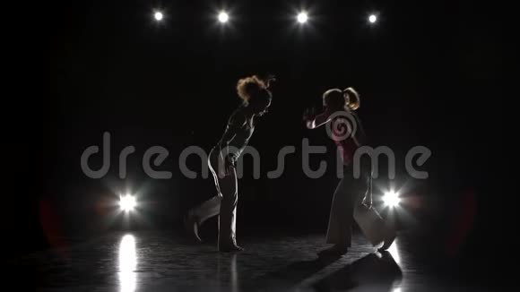 两个女人正在黑暗中练习卡波伊拉对抗聚光灯视频的预览图