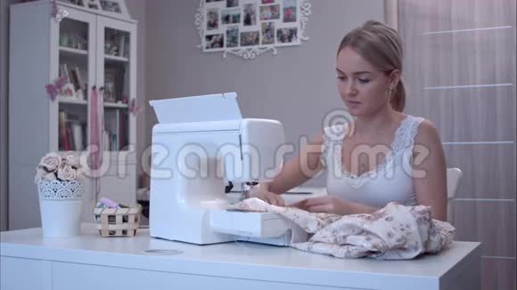 有魅力的年轻女子在缝纫时接电话视频的预览图