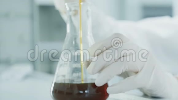 双手研究人员将油滴到实验室试管中视频的预览图