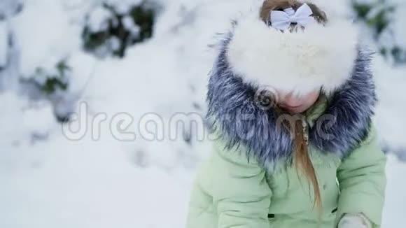 在冬季景观的背景下女孩在院子里玩雪扔洒雪视频的预览图