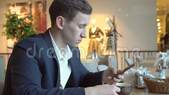 一个年轻的帅哥在咖啡馆的桌子上打电话视频的预览图