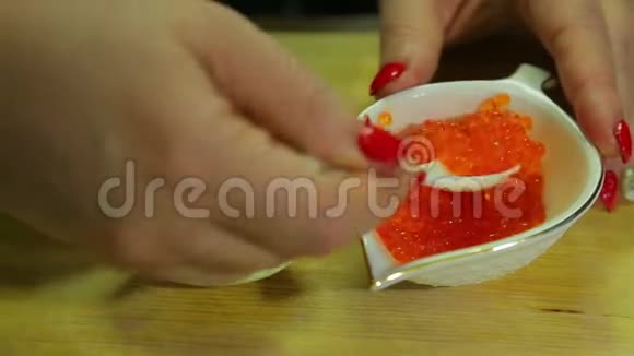 一个女人在半个煮鸡蛋上勺着红色鱼子酱视频的预览图