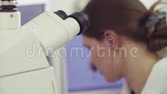 显微镜附近的年轻女科学家视频的预览图