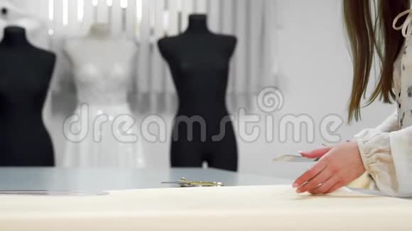 美丽的时装设计师女孩剪在纸上金色剪刀图案的织物在人体模特的背景上穿着视频的预览图