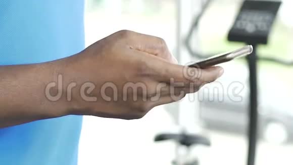 多种族男性在健身房跑步机上行走时使用手机视频的预览图