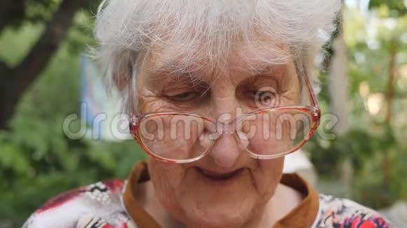 戴眼镜的老妇人在户外看东西和微笑戴眼镜的快乐奶奶在外面度过时光的画像视频的预览图
