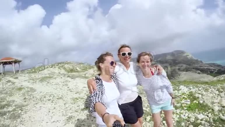 三个年轻女人在岩石顶部自拍海景视频的预览图