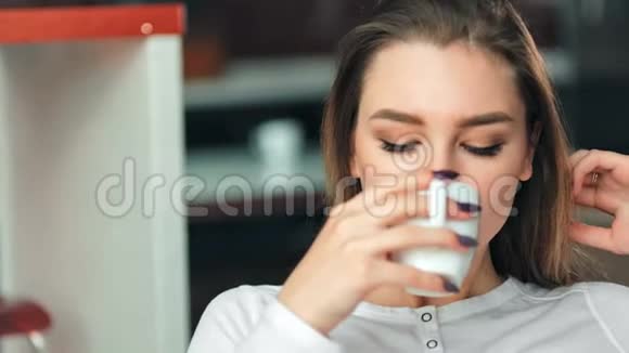 年轻女子坐在椅子上在红色时髦的公寓里喝咖啡视频的预览图