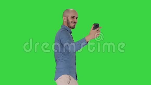 快乐的微笑英俊的年轻人在绿色屏幕上行走时自拍Chroma键视频的预览图