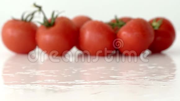 成熟的樱桃西红柿落在白色镜面上背景是西红柿缓慢运动视频的预览图