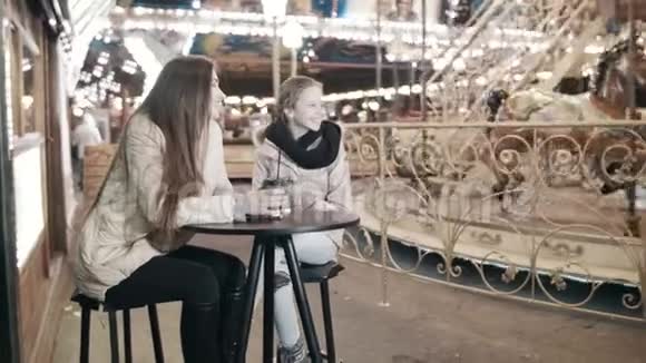 一个女人和一个女孩正坐在游乐园的一个街头咖啡馆桌子旁视频的预览图