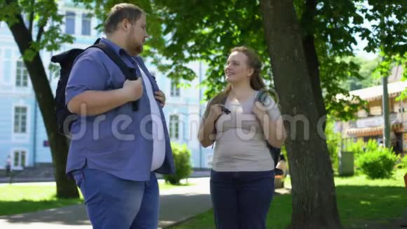 年轻的超重男女牵着手在公园里滋滋作响学生们喜欢视频的预览图
