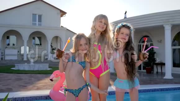 在泳池和别墅附近的摄像机上摆姿势的被宠坏的孩子暑假穿泳衣的儿童名人富有的孩子视频的预览图