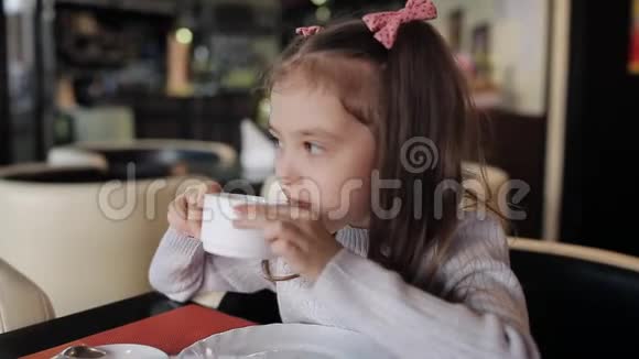 一个漂亮的小女孩在咖啡馆吃饭喝着香茶视频的预览图