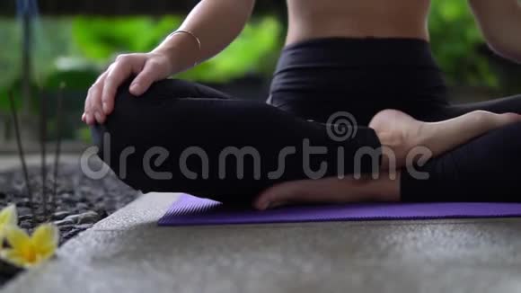 靠近低镜头的女孩腿和手坐在瑜伽姿势的垫子户外视频的预览图