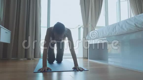 穿着西装在室内垫子上做运动的年轻瘦妇视频的预览图