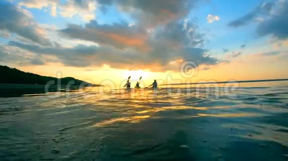 一群划手正在划着皮划艇进入日落视频的预览图