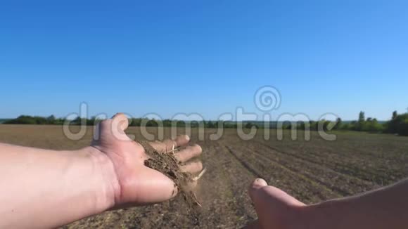 男农手握一把干地实地检查土壤肥力年轻人的武器倒在地上视频的预览图