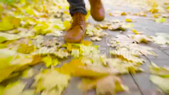 一个穿皮鞋的年轻人走在一条有落叶的人行道上视频的预览图