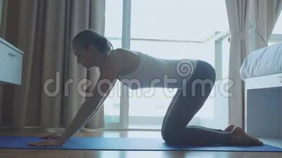 穿着西装在室内垫子上做运动的年轻瘦妇视频的预览图