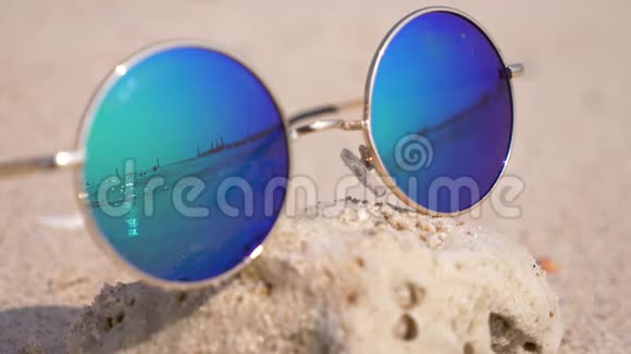 太阳镜躺在沙滩上的沙滩上太阳镜反射大海太阳天空海滩4k慢动作视频的预览图