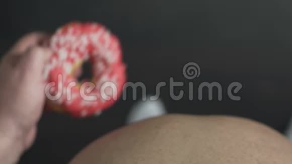 超重男性食用含粉色釉的高热量甜甜圈肥胖的俯视图视频的预览图