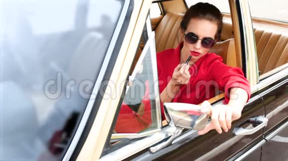 戴着黑色太阳镜的漂亮女人坐在复古车里化妆视频的预览图
