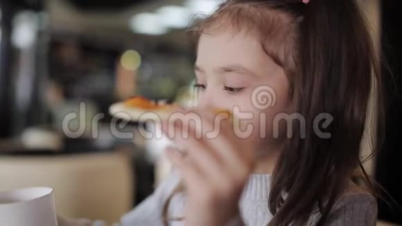 一个小女孩在吃着一块带有拉伸奶酪的披萨特写视频的预览图