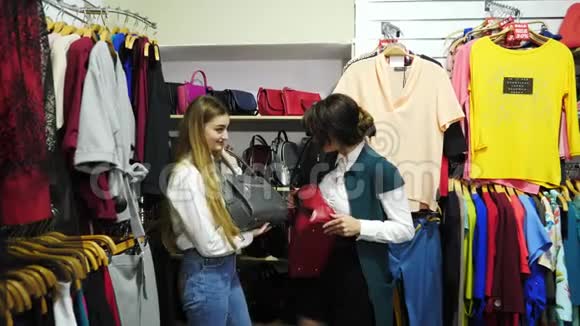 在精品店里漂亮的年轻女孩挑选和处理由皮革制成的袋子视频的预览图