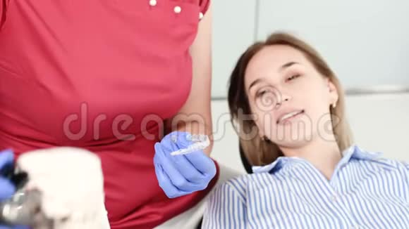 女牙医向年轻女性病人展示和解释石膏模型的问题视频的预览图