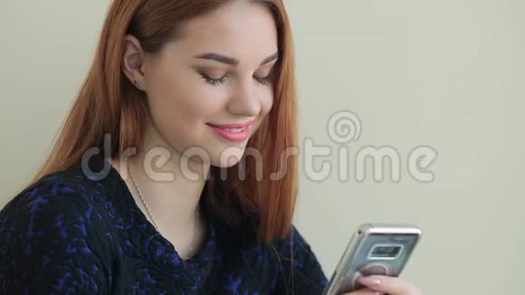 美丽的年轻女子在家坐在窗台上通过电话在社交网络上交流视频的预览图