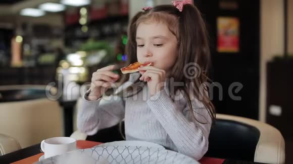 穿粉色衣服的快乐女孩在披萨店吃开胃披萨视频的预览图