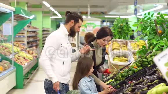 年轻快乐的父母带着孩子在超市买蔬菜视频的预览图