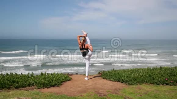 年轻的金发女人在海洋附近练习瑜伽姿势视频的预览图
