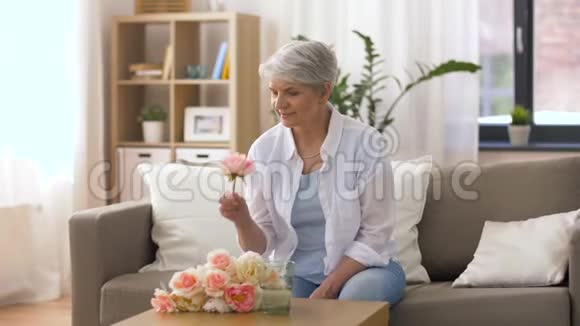 快乐的老妇人在家给花瓶放花视频的预览图