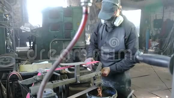 在皮带研磨机上研磨金属刀的坯料工人在他的脸上戴着防护面罩执行任务视频的预览图
