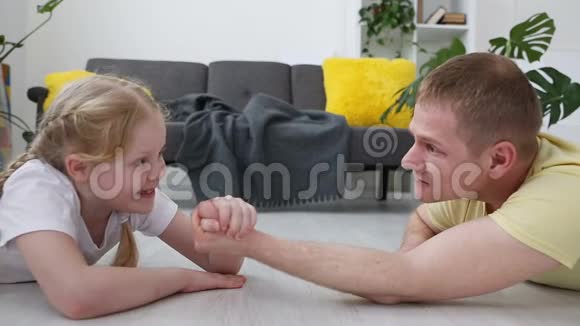 快乐的现代家庭爸爸和他的小女儿是用客厅地板上的力来衡量的视频的预览图