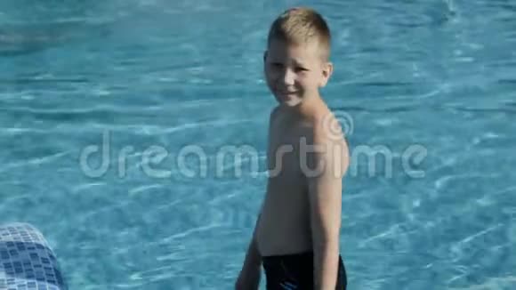 穿着黑色泳裤的小男孩跳进蓝色的游泳池视频的预览图