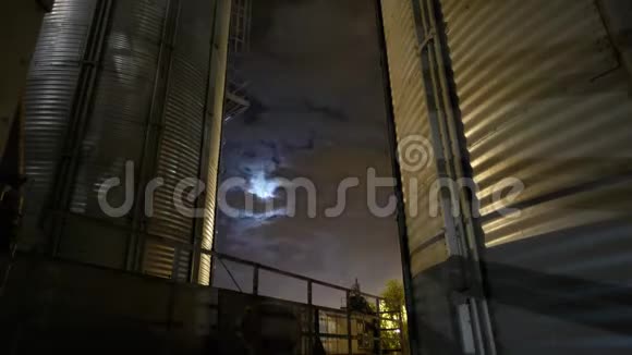 晚上谷物码头的时间点天上的月亮和云电梯的金属罐谷物干燥厂视频的预览图