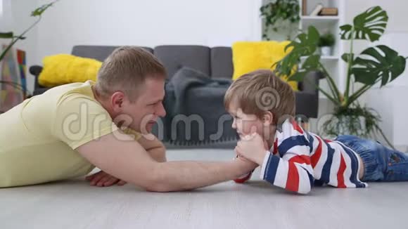 快乐的现代家庭爸爸和他的小儿子是用客厅地板上的力来衡量的视频的预览图