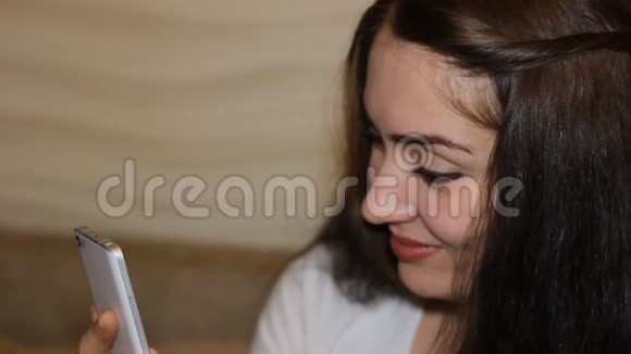 幸福的年轻女人手里拿着一部手机美丽的女孩黑发在网上交流看着视频的预览图