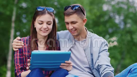 小女孩和一个男人在公园里用平板电脑男孩拥抱女孩视频的预览图